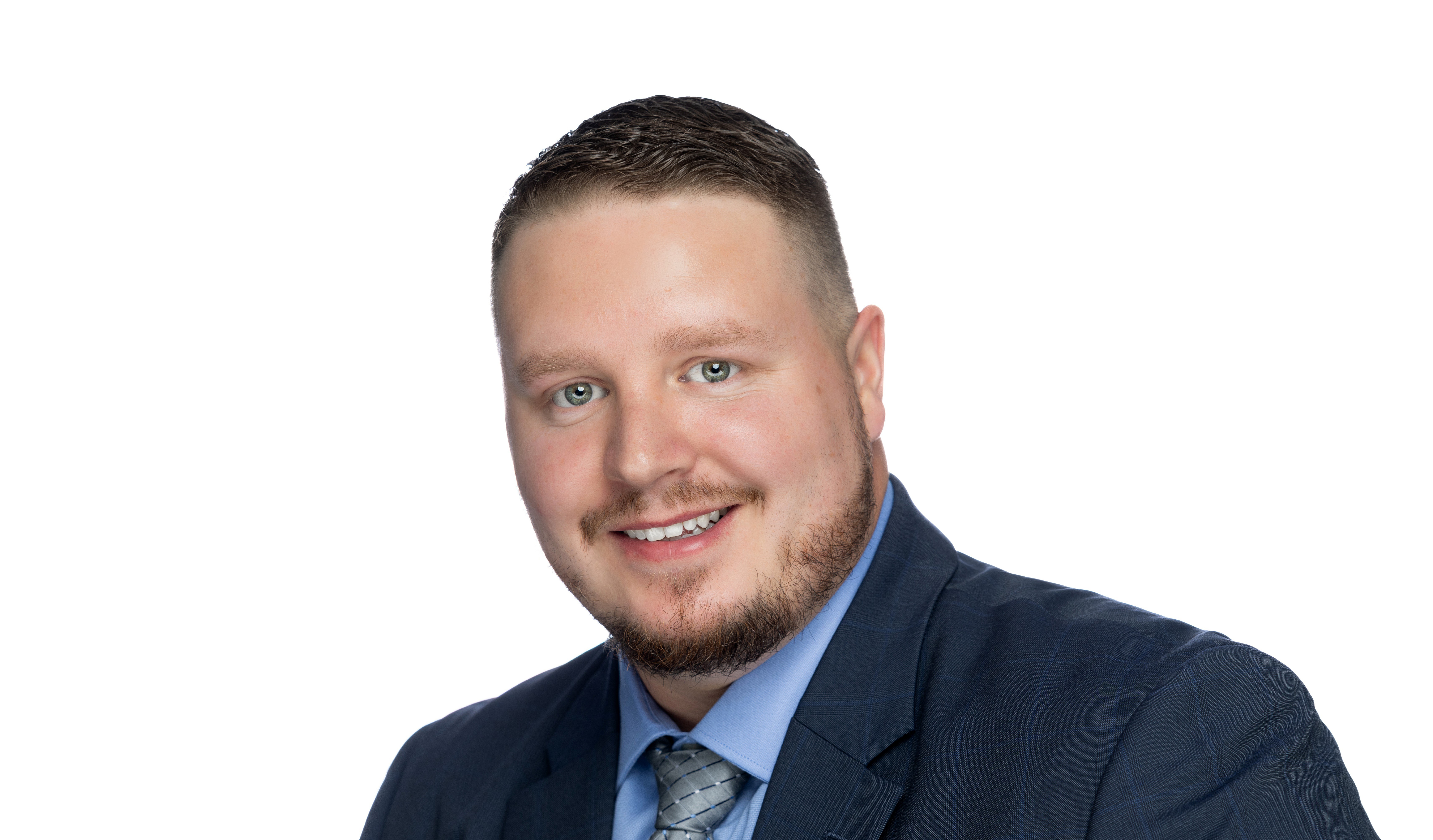 Picture of man smiling for a company headshot in a suit with a white background.